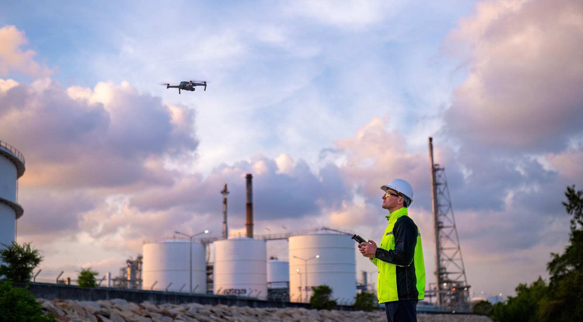 Engineer surveyor team under used drone camera for operator inspecting and survey construction site with gas oil refinery background